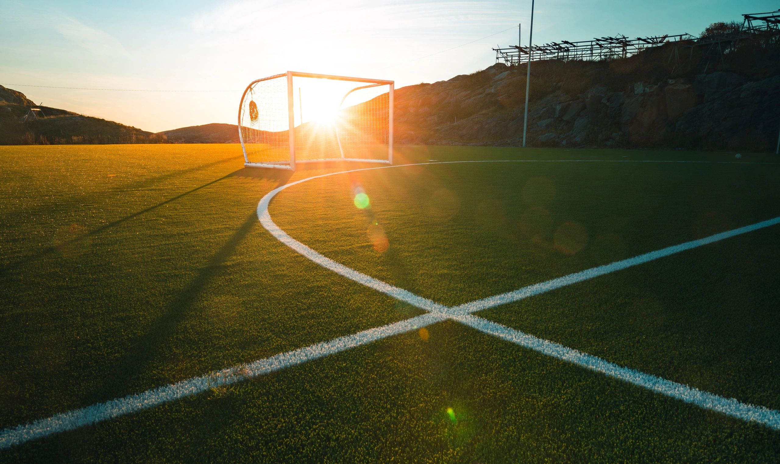 Campo de fútbol al atardecer con rayos de sol