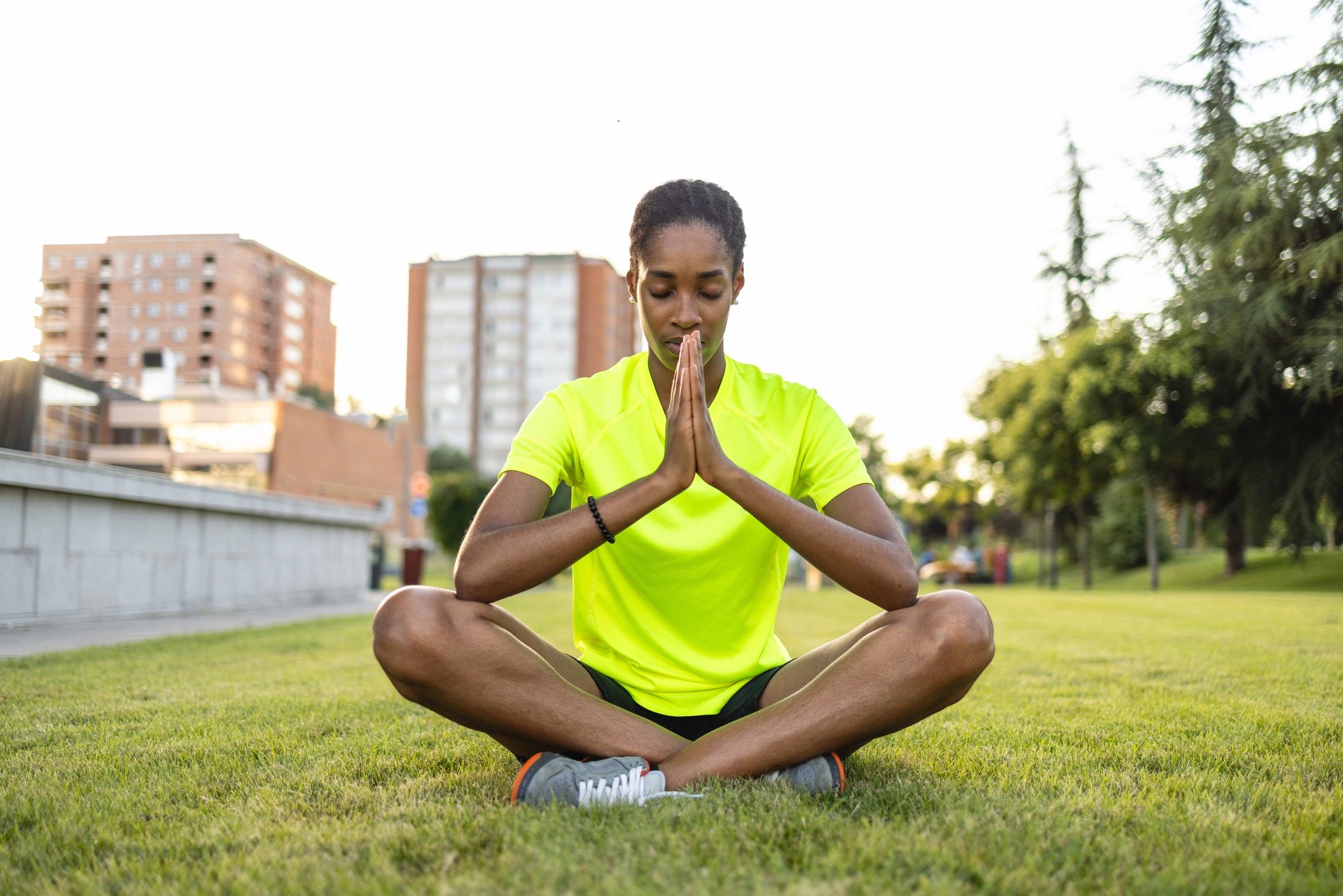 Deportista meditando al aire libre, práctica de respiración y calma
