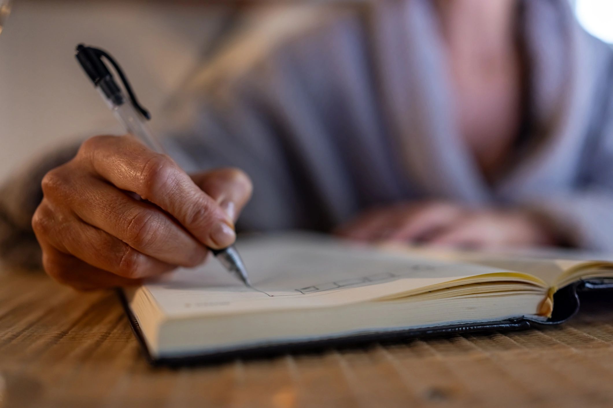 Mano escribiendo en un cuaderno, símbolo de reflexión y aprendizaje